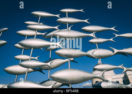 Statue de poisson argenté chiffres sur poteaux. Statue métallique de plusieurs poissons avec ciel bleu en arrière-plan. Banque D'Images