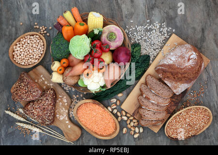 Riche en fibres alimentaires de santé naturel avec du pain de seigle à grains entiers et les petits pains, les légumes, les légumineuses, les graines, les noix et les céréales sur en arrière-plan. Banque D'Images