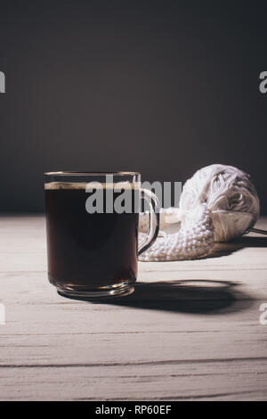 Tasse de café noir sur la table à côté du tricot, close-up. Banque D'Images