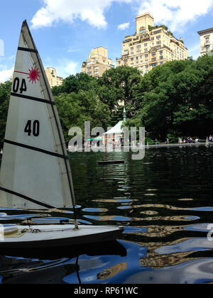 Gros plan du modèle commandé à distance voilier glissent sur étang dans Central Park NYC Banque D'Images