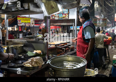 L'atmosphère typique occupé nuit bruyante scène de rue à Calcutta avec un fournisseur d'aliments de rue faisant un Paratha Placez Mughlai Bengali populaire street food. Banque D'Images