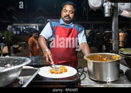 L'atmosphère typique occupé nuit bruyante scène de rue à Calcutta avec un fournisseur d'aliments de rue faisant un Paratha Placez Mughlai Bengali populaire street food. Banque D'Images