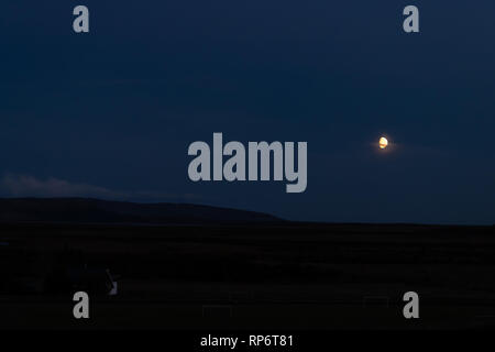 Vue paysage de Lune se levant au-dessus du lac Laugarvatn sur cercle d'or en Islande pendant le crépuscule bleu violet des couleurs sombres et des terres Banque D'Images