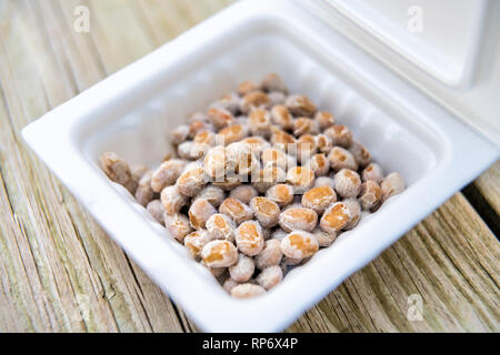 Gros plan du natto japonais asiatiques congelés plat de soja fermenté contenant en styromousse repas au Japon fort sur macro table en bois Banque D'Images