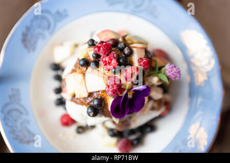 Télévision Vue de dessus de la crème glacée faite maison végétalien premières baies et fruits frais du jardin sur la plaque avec le sirop et la garniture date pansy violet fleur comestible Banque D'Images