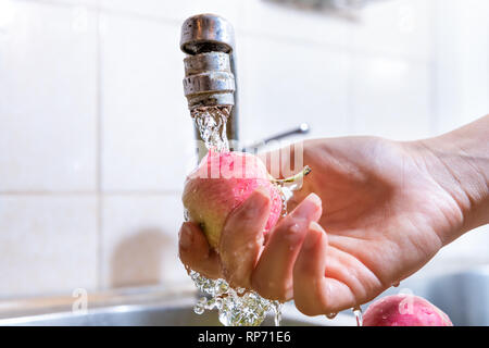 Un lave-mains pink lady apple par lavabo avec robinet de gros plan montrant le détail et la texture des gouttes dans la maison avec mur carrelé Banque D'Images