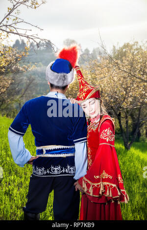 Couple en costume Kazakh au printemps Blooming garden apple au coucher du soleil d'Almaty, Kazakhstan, en Asie centrale Banque D'Images