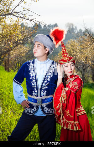 Couple en costume ethnique kazakhe en fleurs de printemps dans le jardin d'apple d'Almaty, Kazakhstan, en Asie centrale Banque D'Images