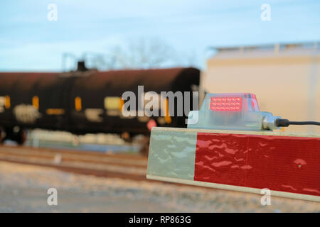 Close-up de la fin pointe d'une barrière de fer à un niveau de la rampe de passage à niveau avec un train passant par en arrière-plan ; Bryan, Texas, USA. Banque D'Images