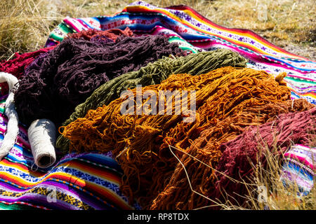 Filé teint coloré sur inca traditionnel couverture tissée sur l'herbe au soleil. Banque D'Images