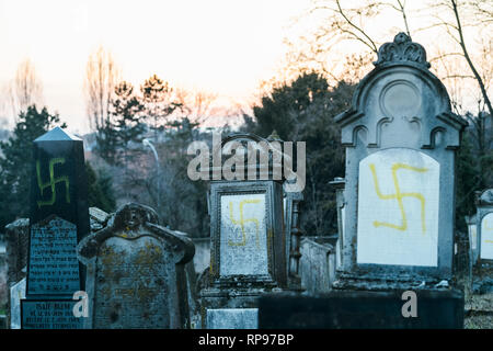 Des tons bleu froid image de vandalisé tombes avec des croix gammées des symboles nazis en bleu peint sur les tombes endommagées - cimetière juif à Quatzenheim près de Strasbourg Banque D'Images