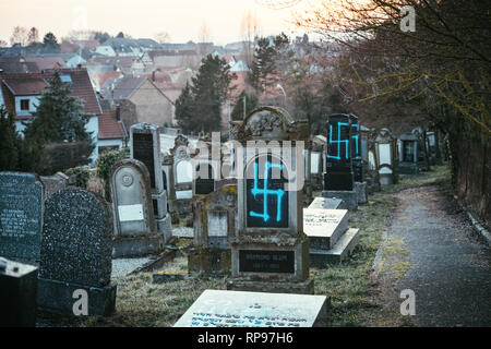 Vue en perspective sur les tombes vandalisées dans avec des symboles nazis en bleu peint sur les tombes endommagées - cimetière juif à Quatzenheim près de Strasbourg Banque D'Images