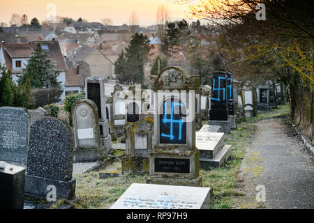 Coucher de soleil sur plusieurs tombes vandalisées de croix gammées des symboles nazis en bleu peint sur les tombes endommagées - cimetière juif à Quatzenheim près de Strasbourg Banque D'Images