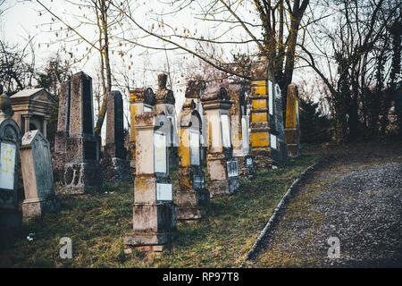 Vue de côté plusieurs tombes vandalisées avec des symboles nazis en jaune peint sur les tombes endommagées - cimetière juif à Quatzenheim près de Strasbourg Banque D'Images