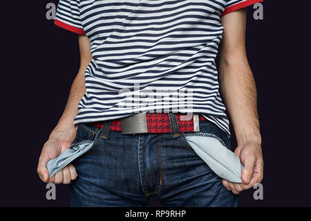 Pauvre homme en jeans avec poche vide isolé sur noir. Le mec tient la main vide poches jeans. Guy démontre son échec de la pauvreté et l'absence de mo Banque D'Images
