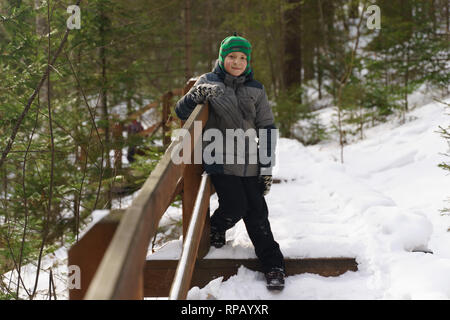 Garçon sur un sentier de randonnée dans la forêt d'hiver. Clôtures en bois. Krasnoyarsk, la réserve Stolby Banque D'Images