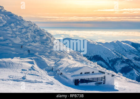 Les pics d'hiver de montagnes dans le matin ensoleillé. La brume dans les vallées. Cafe De la neige et deux touristes méconnaissable Banque D'Images