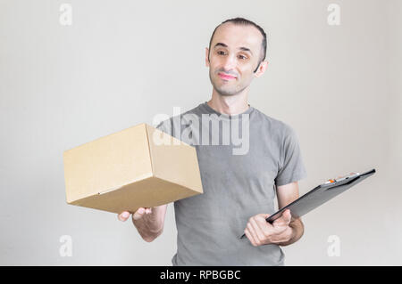 Smiling delivery man with Grey T-shirt portant un colis sur un fond blanc Banque D'Images