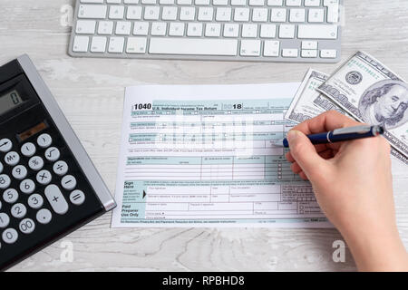 Point de vue, la photo d'une femme le calcul et le remplissage-nous Formulaire d'impôt suivant pour clavier de l'ordinateur, des dollars et formulaire d'impôt 1040. 15 avril 2019 Journée de l'impôt Banque D'Images
