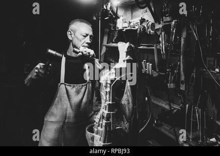 Maître-charpentier 50 - 55 ans crée des sculpture en bois dans l'atelier, la photographie noir et blanc Banque D'Images