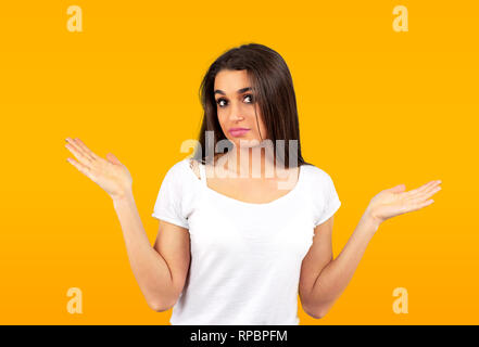 Portrait d'une jeune fille occasionnels confus en haussant les épaules isolé sur fond jaune Banque D'Images