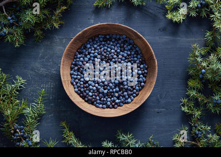 Les baies de genévrier sur et à côté de bol en bois. Les baies de genévrier et les branches. Banque D'Images