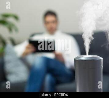 Humidificateur d'air à la salle de séjour. L'homme à l'aide de tablet pc sur l'arrière-plan. Banque D'Images