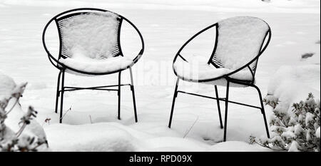 Deux chaises couvertes de neige sur un patio Banque D'Images