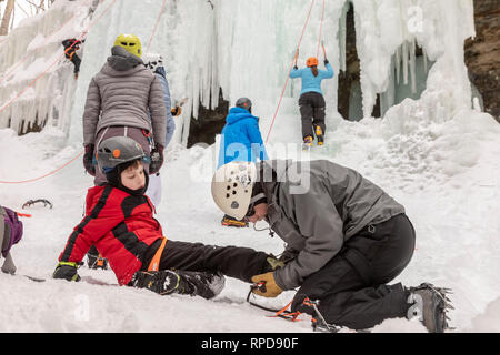 Munising, Michigan - Un garçon obtient de l'aide de crampons raccord avant de grimper un mur de glace au cours de l'assemblée annuelle de glace : le Michigan. Les participants ont grimpé frozen Banque D'Images