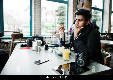 Casual et élégant jeune homme asiatique avec des écouteurs au café de manger des sushis. Banque D'Images