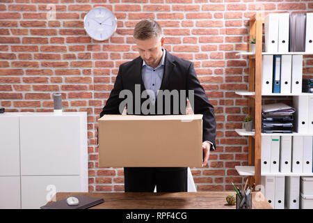 Jeune homme d'affaires dans son emballage Boîte en carton sur le lieu de travail Banque D'Images