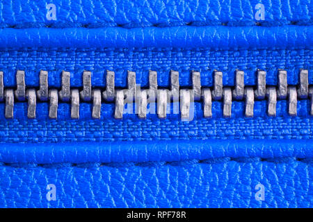 Fermeture éclair en métal sur veste en cuir bleu intense ou bourse détail close up macro. La fermeture éclair est bien fermé enserrant les deux couches textiles avec Banque D'Images