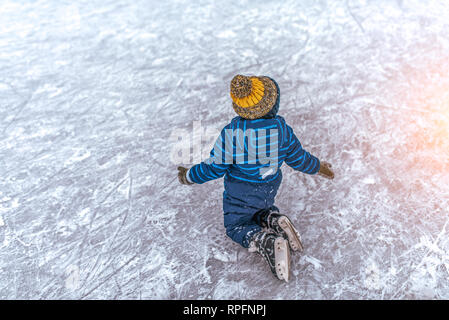 Petit garçon de 2-3 ans, en jupe, est tombé sur la glace ses patins. Concept première leçon de skating support , l'échec et à l'automne, apprendre à jouer des sports Banque D'Images