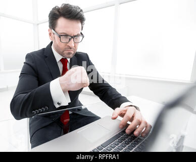 Vérification des comptes d'affaires graves alors qu'il était assis à son bureau. Banque D'Images
