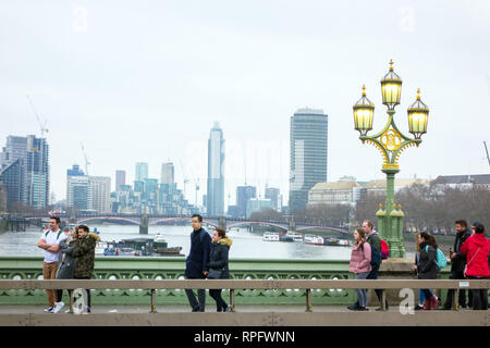 Les gens marcher sur le pont de Westminster avec tête triple lampadaire en fonte avec les lumières allumées sur la tamise Angleterre Londres Banque D'Images