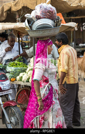 Femme en costume traditionnel portant sur la tête des ustensiles, Jaisalmer, Rajasthan, India Banque D'Images