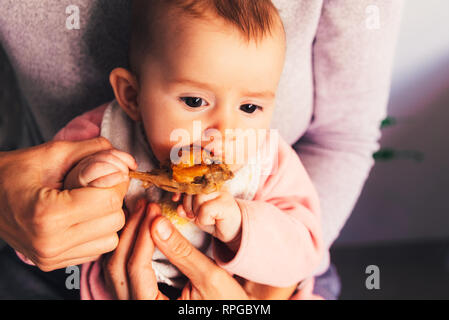 Bébé âgé de 5 mois de manger une cuisse de poulet à l'aide de l'enfant conduit le sevrage BLW méthode. Banque D'Images