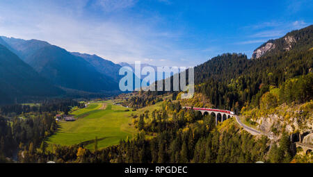 Vue panoramique d'un train rouge traversant le viaduc de Landwasser dans les Alpes Suisses Banque D'Images