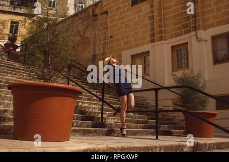 Fille assise sur les grilles de l'escalier sur la rue, vieille ville des trois villes, Malte Banque D'Images