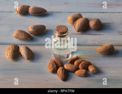 L'huile d'amandes dans un bocal en verre avec bouchon en liège, avec les amandes naturelles sur un fond de bois blanc Banque D'Images