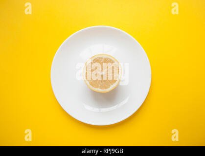 Citron juteux frais mûrs sur plaque blanche sur fond jaune vif. Concept minimaliste. Banque D'Images