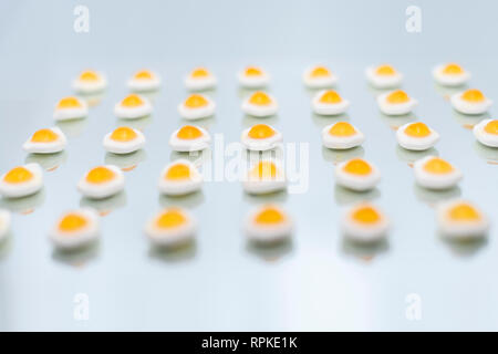 Bonbons en forme d'oeuf et quelques flous sur un miroir et un fond de couleur bleu clair Banque D'Images