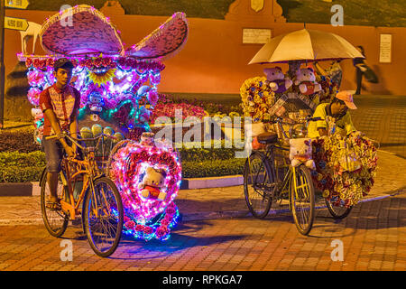 Les trishaws colorés, une forme de location-powered, pousse-pousse que dans la nuit de croisière autour de la ville de Malacca Ville Banque D'Images