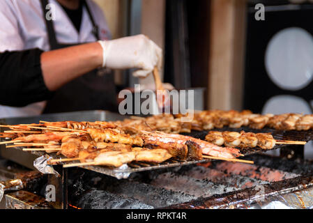 Scène de rue à Osaka, Japon, en tant que chef bastes brochettes de diverses viandes à vendre Banque D'Images