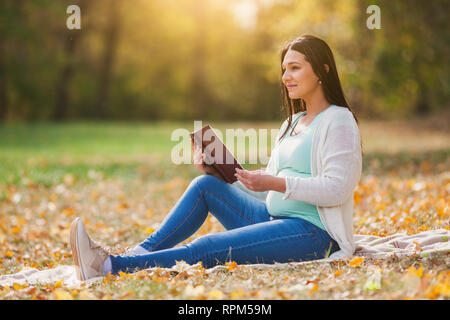 Pregnant woman relaxing in park. Elle est la lecture de livre. Banque D'Images