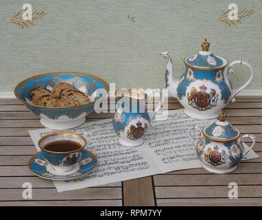 Verre d'anglais avec soucoupe, théière, sucrier, pot à crème et un gâteau bol avec les cookies, céramique fine porcelaine, sur une feuille de musique Banque D'Images