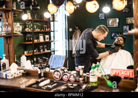 Salon de coiffure de la barbe d'un bel homme barbu avec un rasoir électrique au salon de coiffure . Banque D'Images