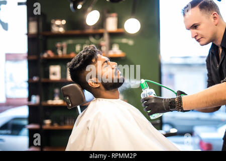 Barbu souriant peignage des cheveux coiffure et la pulvérisation de gamin Banque D'Images