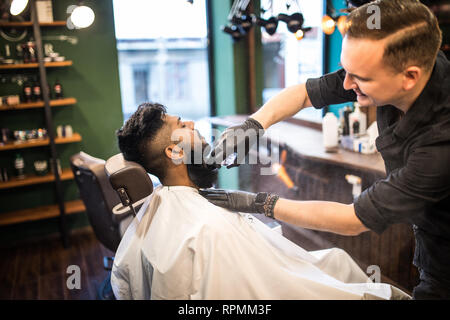 Salon de coiffure de la barbe d'un bel homme barbu avec un rasoir électrique au salon de coiffure . Banque D'Images