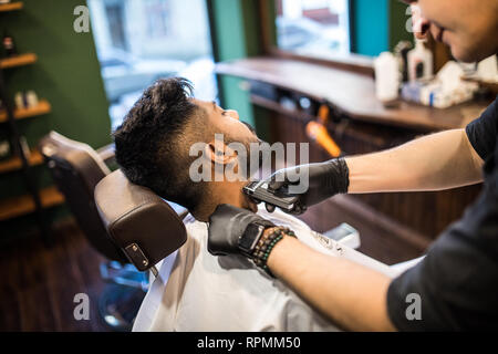 Salon de coiffure de la barbe d'un bel homme barbu avec un rasoir électrique au salon de coiffure . Banque D'Images